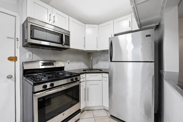 a kitchen with stainless steel appliances white cabinets white stove a microwave and a refrigerator