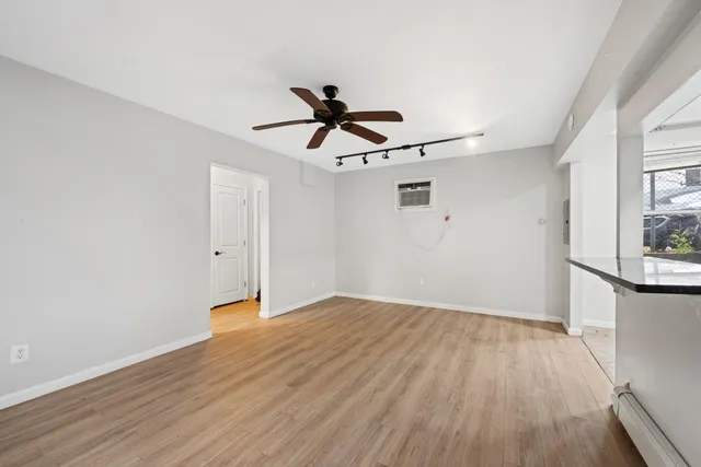 a view of empty room with wooden floor and fan