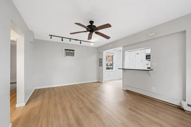 a view of empty room with wooden floor and ceiling fan