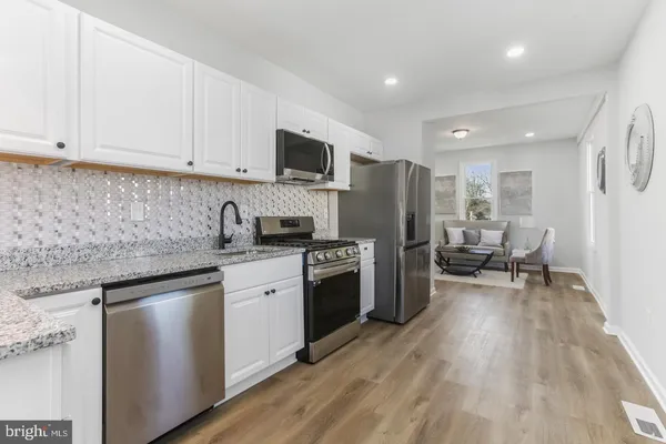 a kitchen with refrigerator a microwave a stove and white cabinets with wooden floor