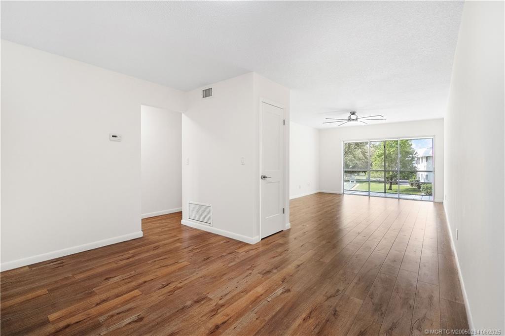 2929 Southeast Ocean Boulevard, Unit 1087 Stuart, FL 34996 - Photo 7 of 21 an empty room with wooden floor and windows