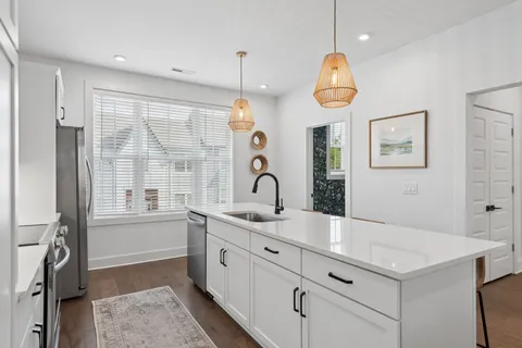 a kitchen with stainless steel appliances a table chairs stove and white cabinets