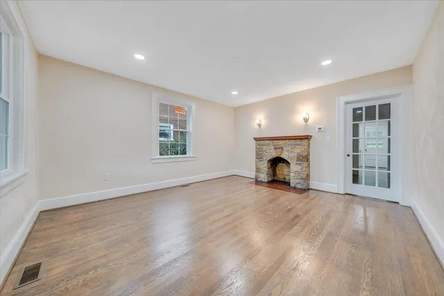 an empty room with wooden floor fireplace and windows