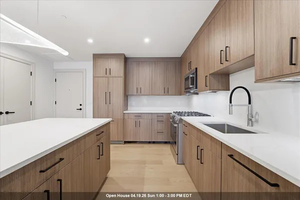 a large kitchen with a sink and dishwasher a refrigerator with wooden cabinets