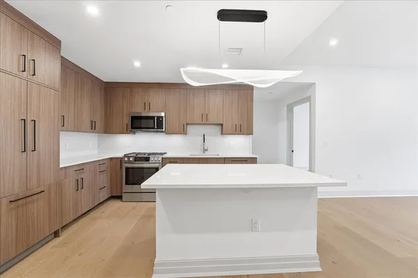 a large kitchen with stainless steel appliances granite countertop a stove a sink a refrigerator and a microwave