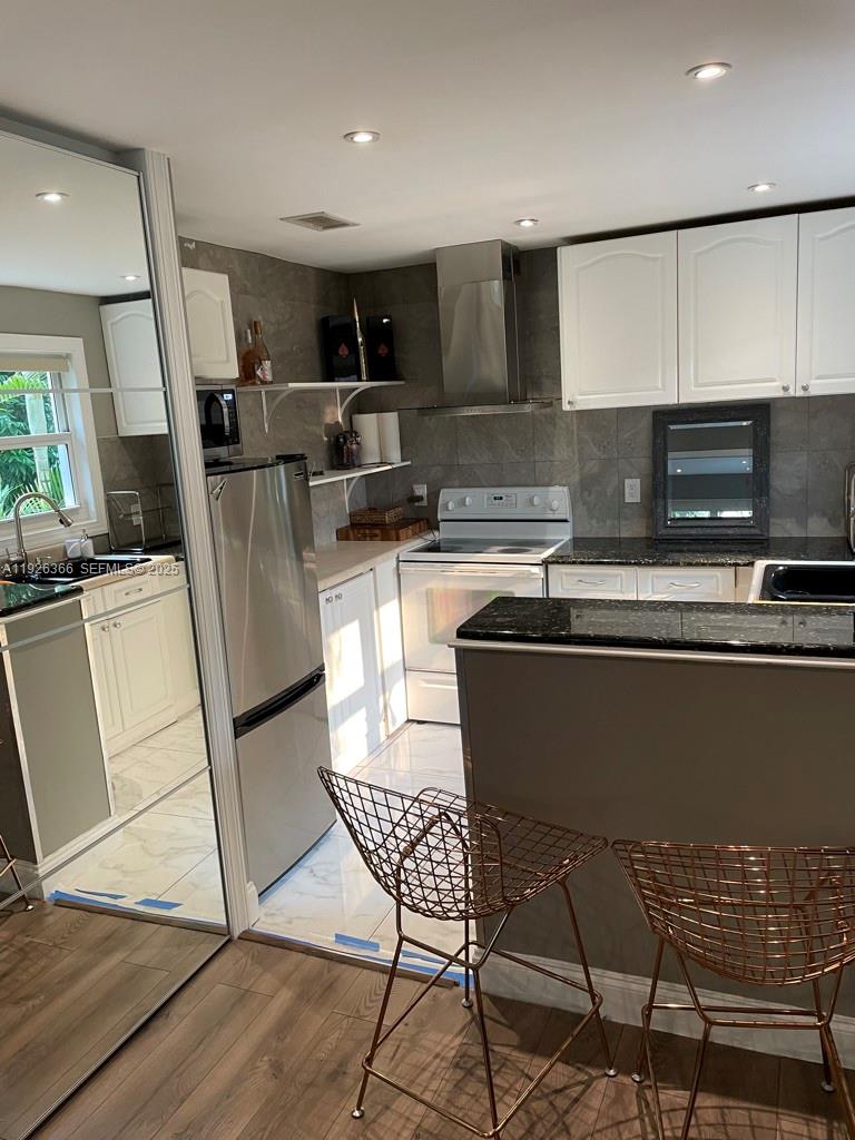 2654 Southwest 25th Terrace Miami, FL 33133 - Photo 10 of 36 a kitchen with stainless steel appliances granite countertop a stove top oven a sink a dining table and chairs
