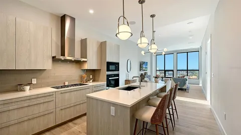 a kitchen with stainless steel appliances kitchen island granite countertop a stove a sink a dining table and chairs with wooden floor