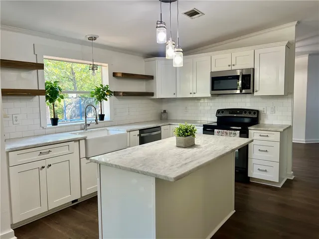 a kitchen with stainless steel appliances granite countertop a stove a sink and a microwave