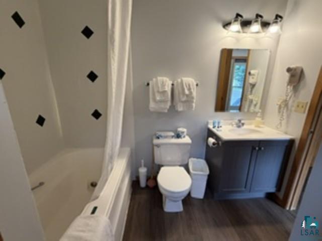 6266 Giants Ridge Road Biwabik, MN 55705 - Photo 13 of 30 Bathroom with wood-finish flooring, a built-in bathtub, a vanity with a white countertop and dark cabinetry, and a wall-mounted light fixture