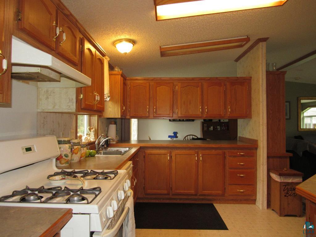 5243 East Neuman Road Superior, WI 54880 - Photo 7 of 35 Kitchen featuring vaulted ceiling, a textured ceiling, light tile floors, white gas stove, and sink