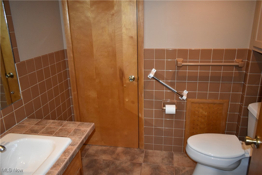 735 Sheridan Road Coshocton, OH 43812 - Photo 22 of 34 Bathroom with tile patterned flooring, vanity, tile walls, and toilet