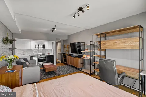 a living room with furniture a flat screen tv and kitchen view