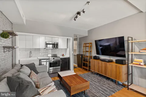a living room with stainless steel appliances furniture and a flat screen tv