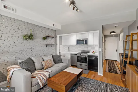 a living room with stainless steel appliances furniture and a kitchen view