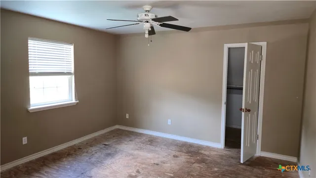 an empty room with a window and a fan