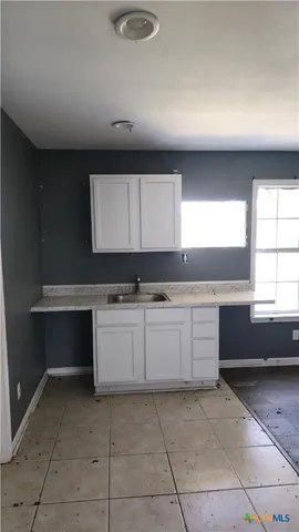 a large kitchen with kitchen island white cabinets and a window