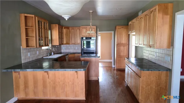a kitchen with granite countertop a sink a counter top space and cabinets