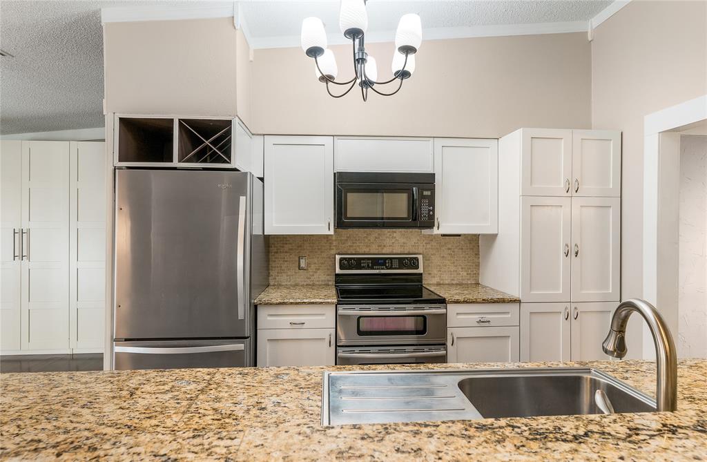 203 Walnut Way Euless, TX 76039 - Photo 17 of 36 a kitchen with stainless steel appliances kitchen island granite countertop a refrigerator a stove and a sink with wooden floor