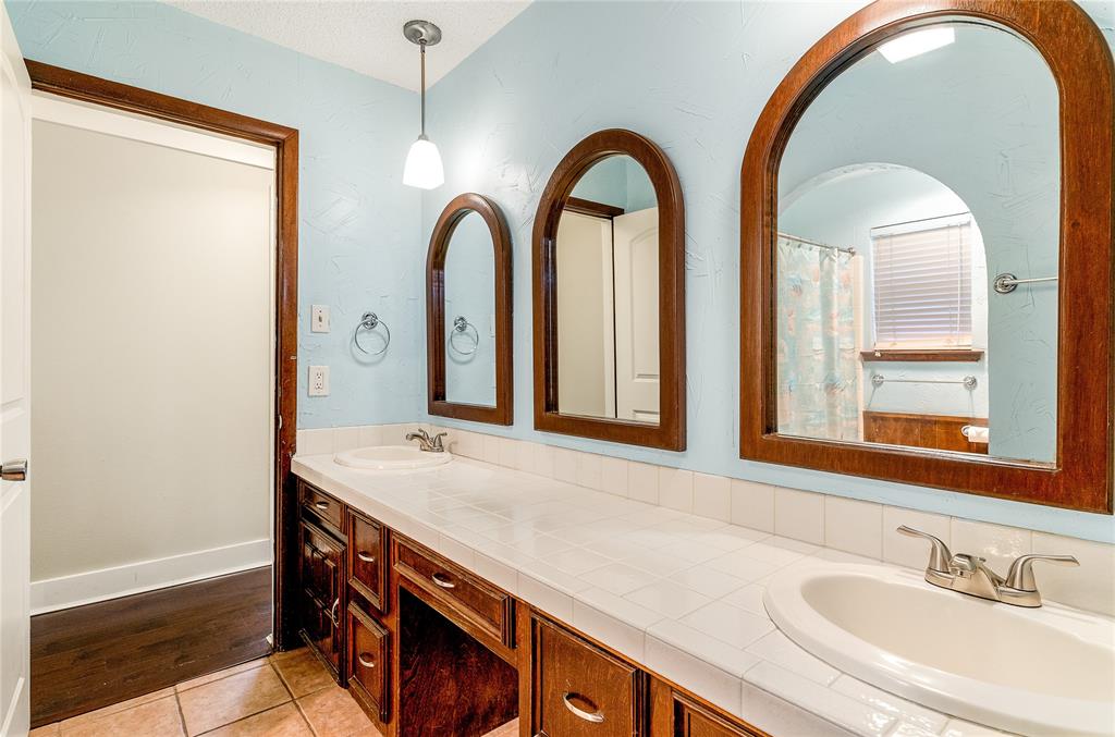 203 Walnut Way Euless, TX 76039 - Photo 21 of 36 a bathroom with a granite countertop sink a mirror and a shower