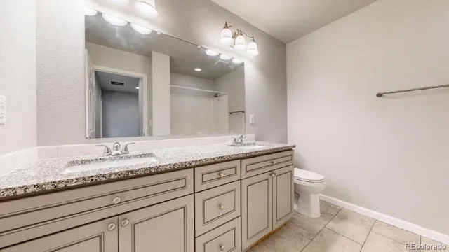 a bathroom with a granite countertop sink a toilet and a mirror