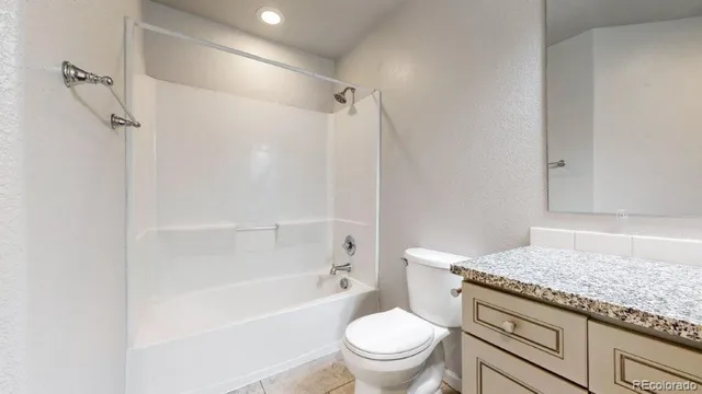 a bathroom with a granite countertop sink toilet and shower