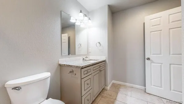 a bathroom with a granite countertop sink a toilet and a mirror
