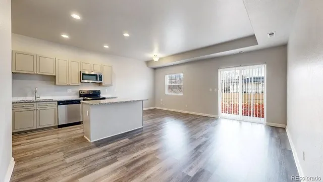 a kitchen with granite countertop a stove a sink and white cabinets with wooden floor