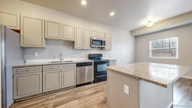 a kitchen with granite countertop white cabinets sink and stainless steel appliances