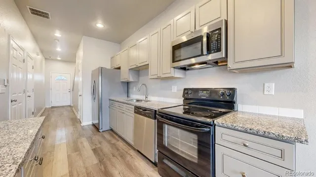 a kitchen with stainless steel appliances granite countertop a stove a sink and a microwave