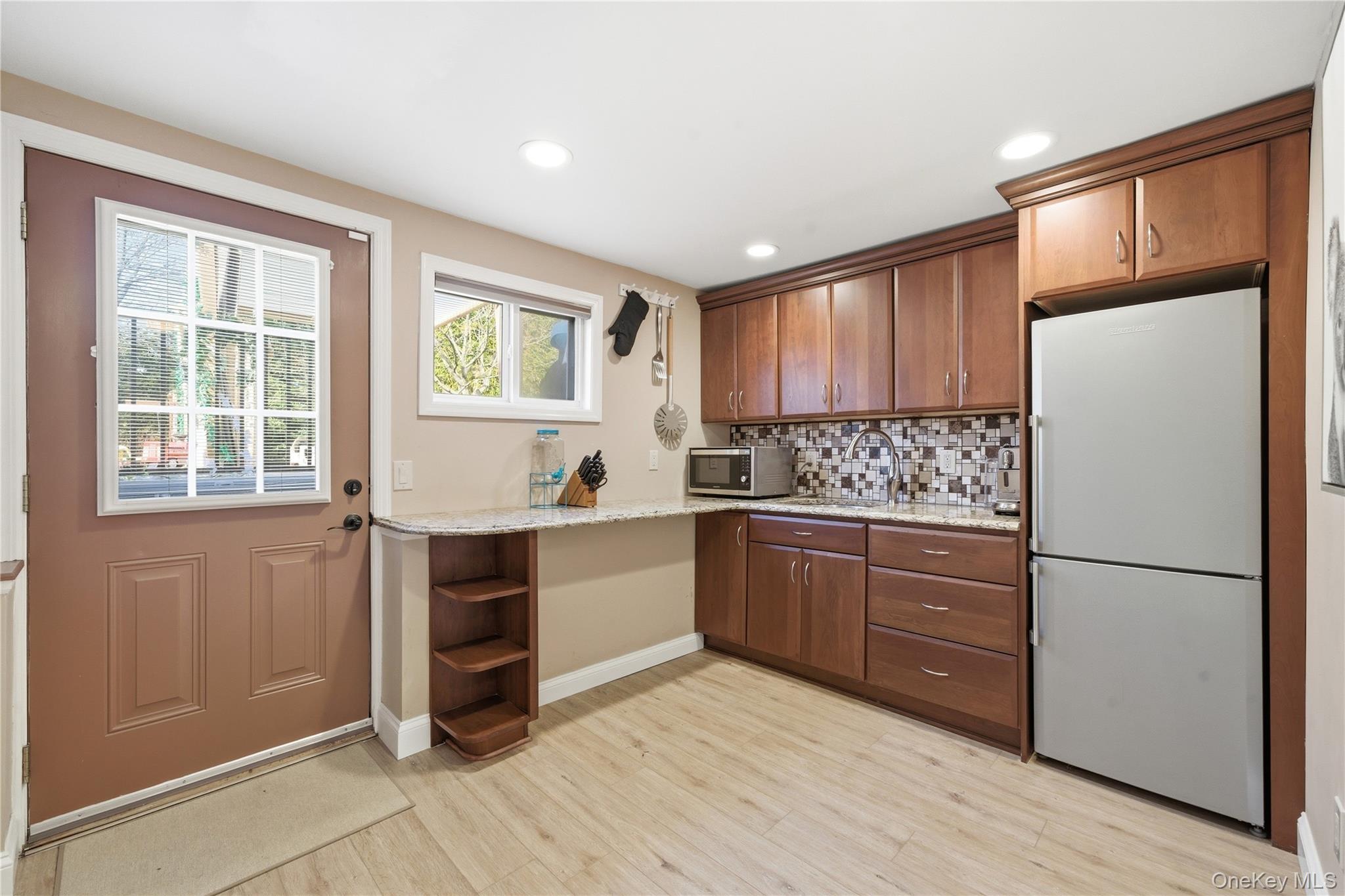 214 Ralph Avenue Babylon, NY 11702 - Photo 22 of 33 a kitchen with granite countertop a refrigerator cabinets and wooden floor