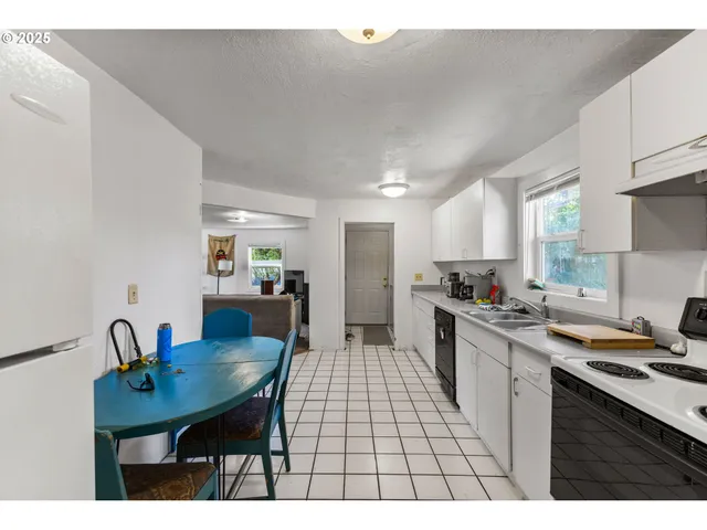 a kitchen with stainless steel appliances a table and chairs in it