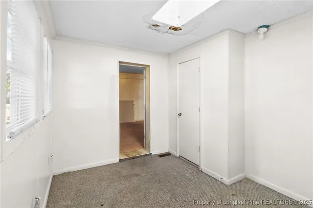 an empty room with windows and chandelier fan