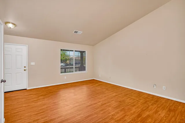 a view of an empty room with wooden floor and a window