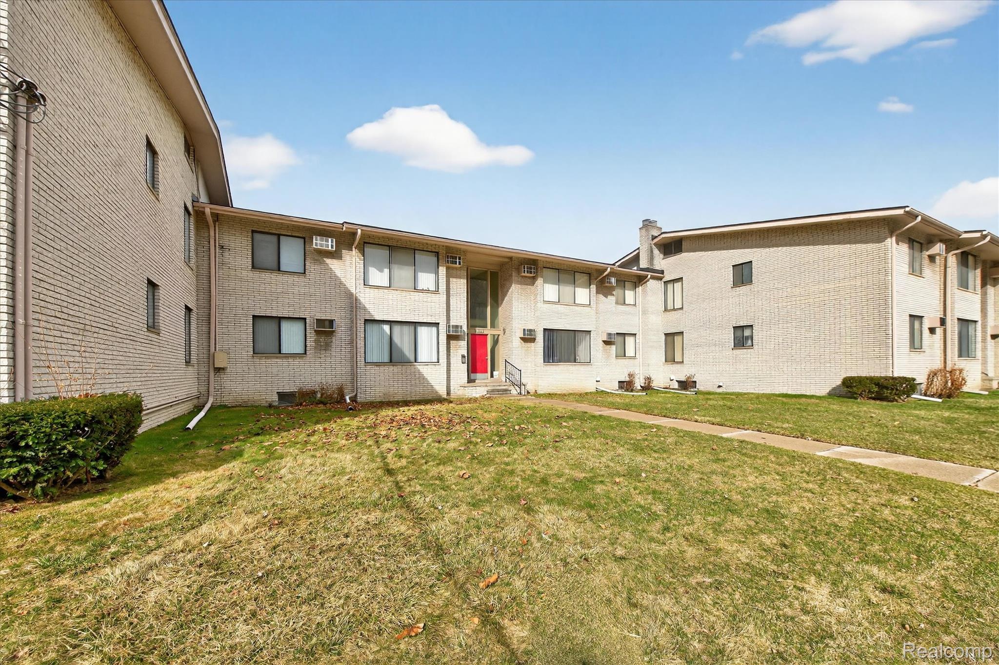 32650 Mound Road, Unit 4 Warren, MI 48092 - Photo 28 of 32 Two-story brick exterior building with multiple windows, a red entry door, and a concrete walkway