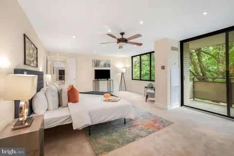 a living room with furniture two large windows and a flat screen tv