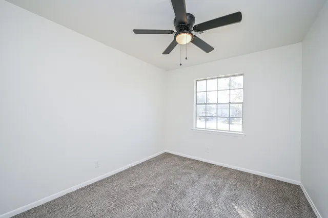 an empty room with a window and a fan