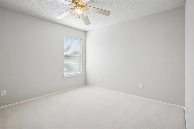 an empty room with a window and a fan
