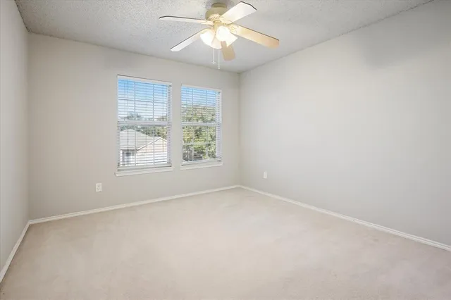 an empty room with a window and a fan