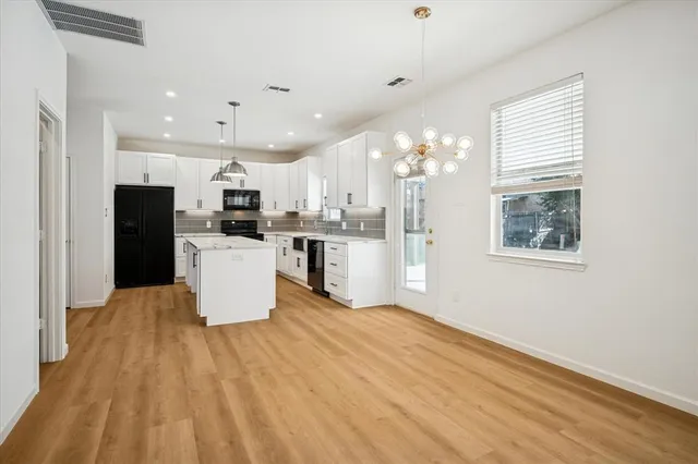 a large white kitchen with wooden floors and stainless steel appliances