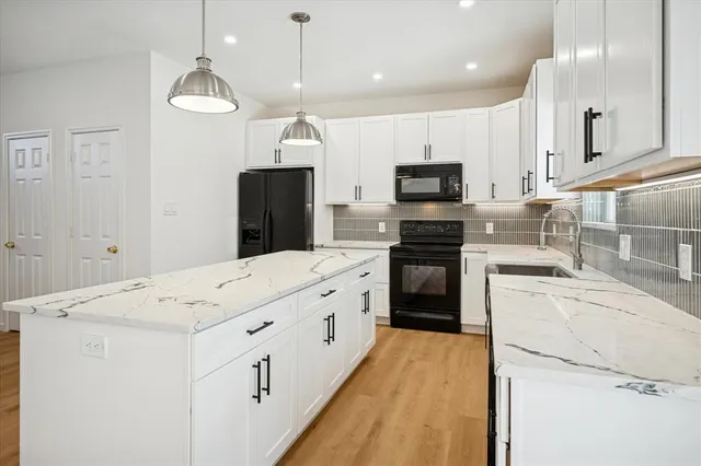 a kitchen with granite countertop a refrigerator stove top oven and cabinets