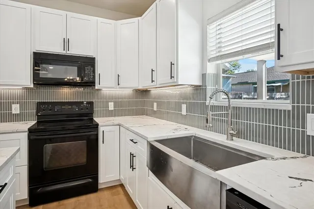 a kitchen with granite countertop a stove a sink and a microwave