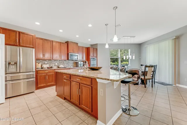 a kitchen with a dining table chairs stainless steel appliances and cabinets