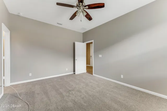 a view of an empty room and chandelier fan