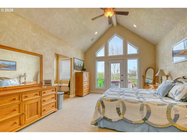 a spacious bedroom with a bed a dresser next to a large window