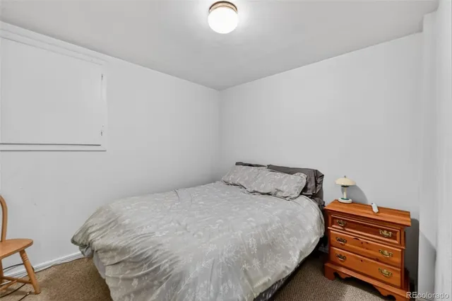 a bedroom with a bed and a lamp on the dresser