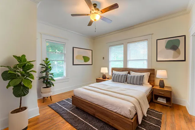 a bedroom with a large bed a chandelier and a potted plant