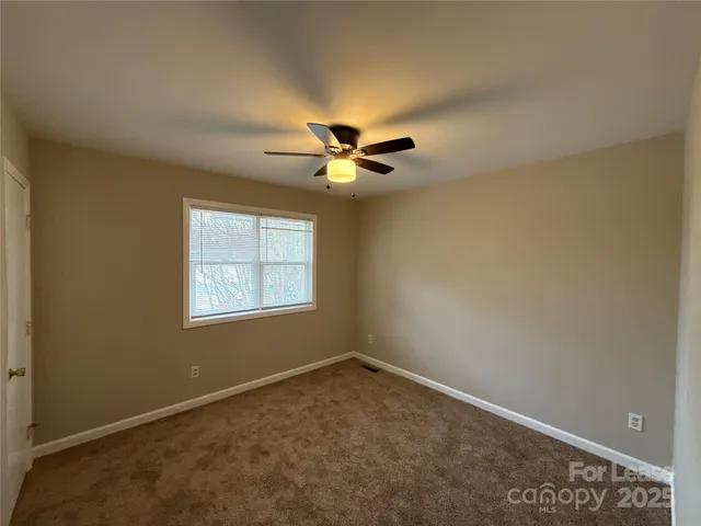 an empty room with a ceiling fan and window