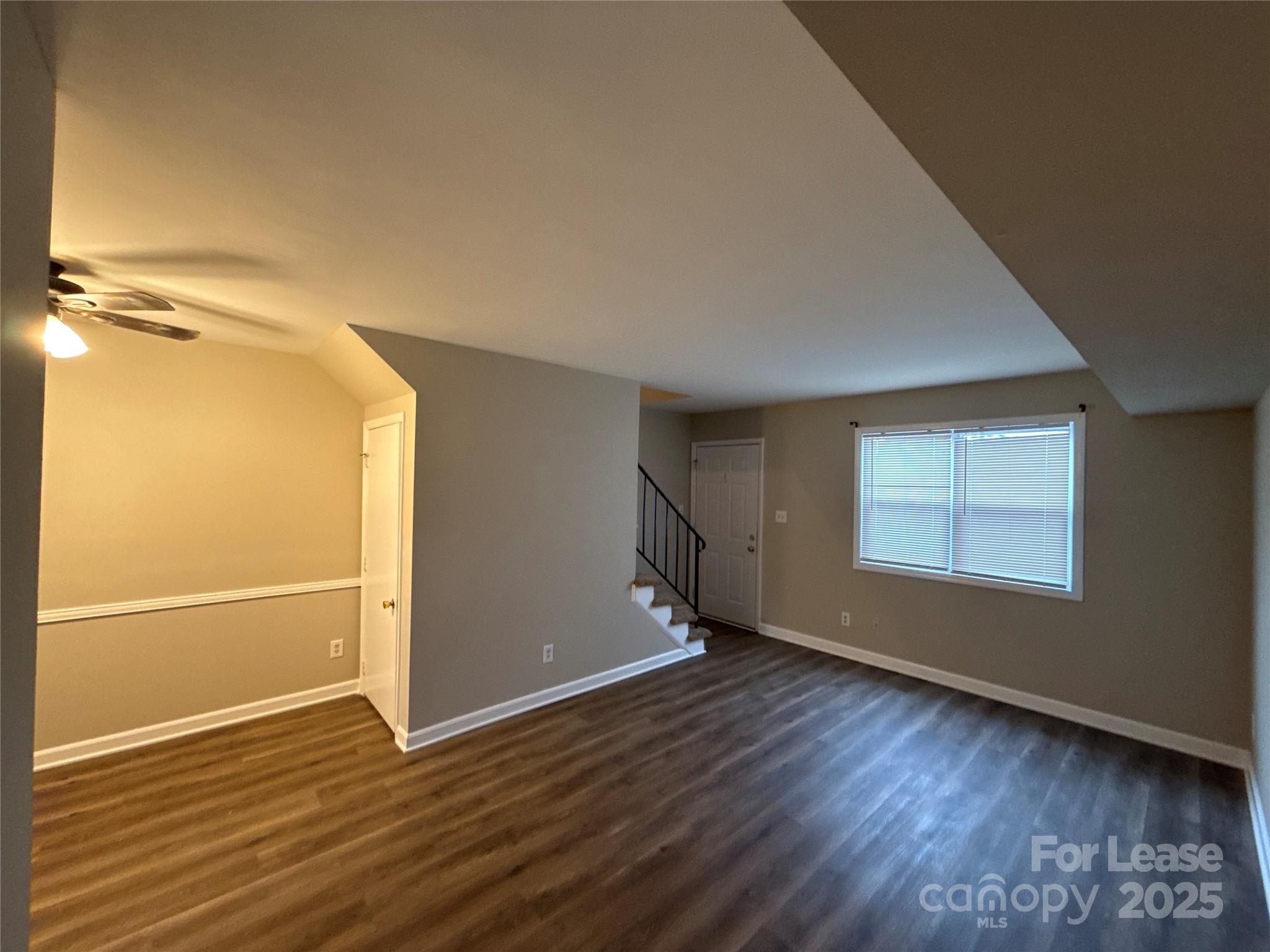 1613 North Sharon Amity Road, Unit H Charlotte, NC 28205 - Photo 2 of 13 an empty room with wooden floor and windows with curtains