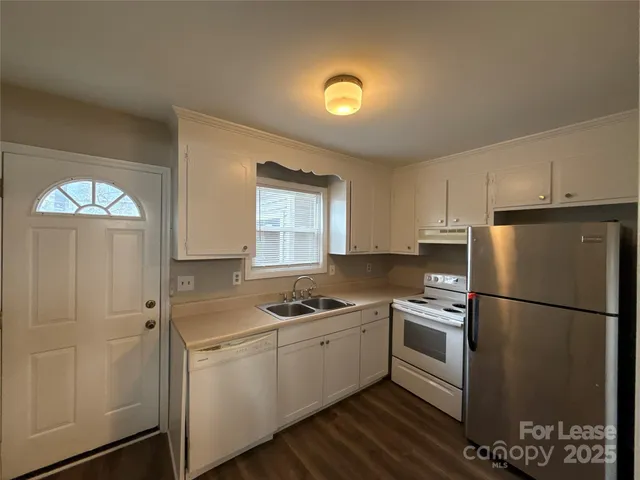 a kitchen with a refrigerator a stove cabinets and wooden floor