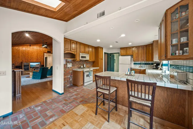 a kitchen with stainless steel appliances granite countertop a refrigerator a stove top oven and a dining table with wooden floor